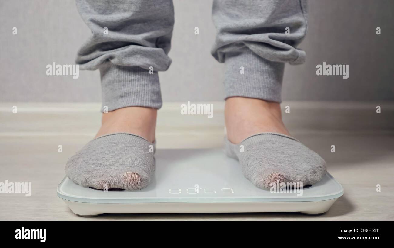 Woman stands on electronic scale to measure weight closeup Stock Photo
