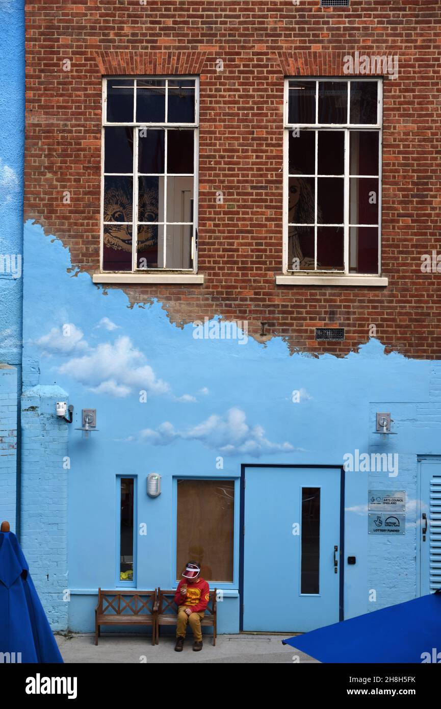 Boy Sitting on Bench in front of Blue Facade, Blue Wall & Blue Door in The Story Museum Oxford England Stock Photo