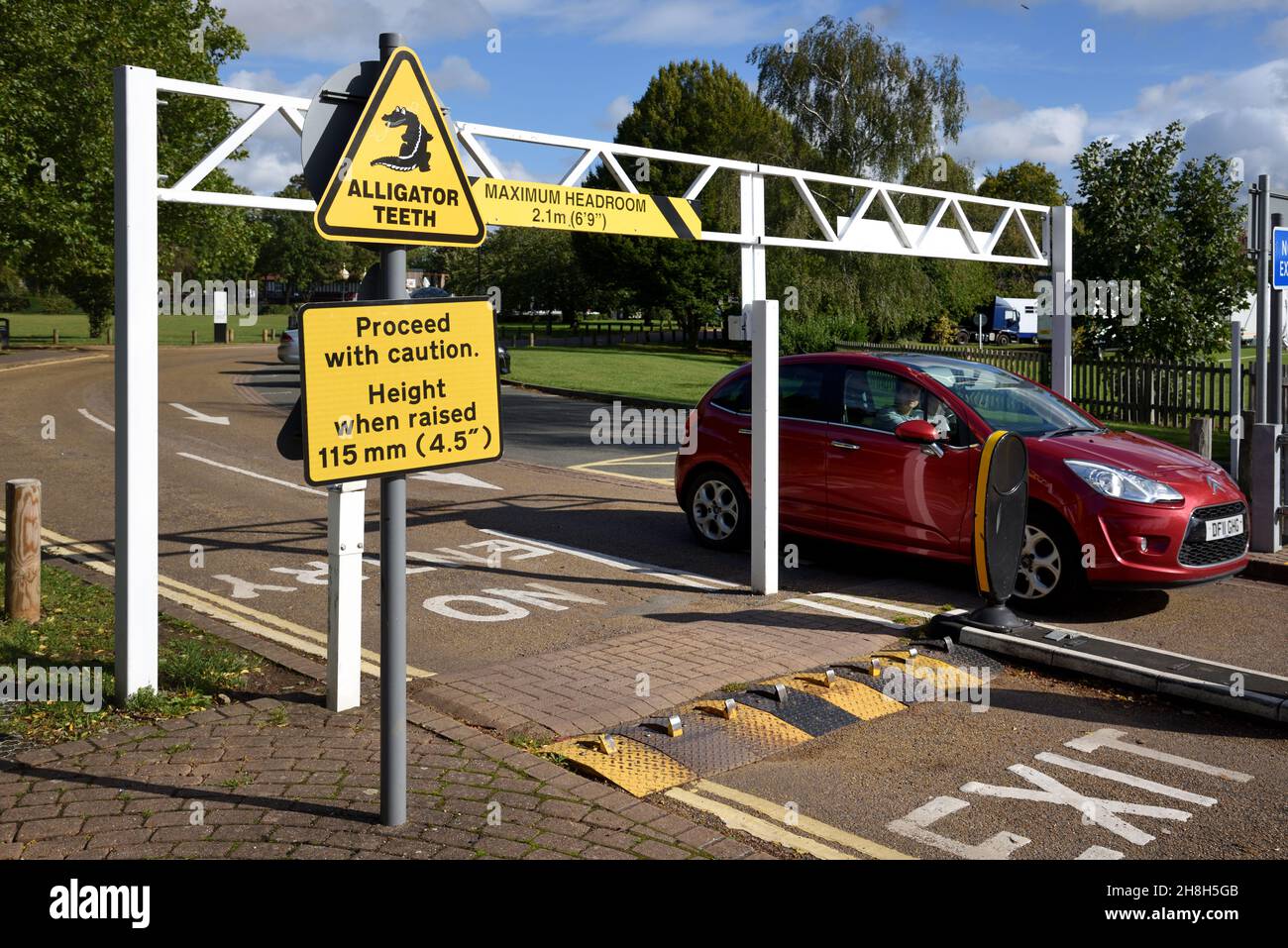 Car Entering Car Park & Sign for Alligator Teeth Traffic Control System or Traffic Direction Enforcers at Entrance or Exit to Car Park Stock Photo