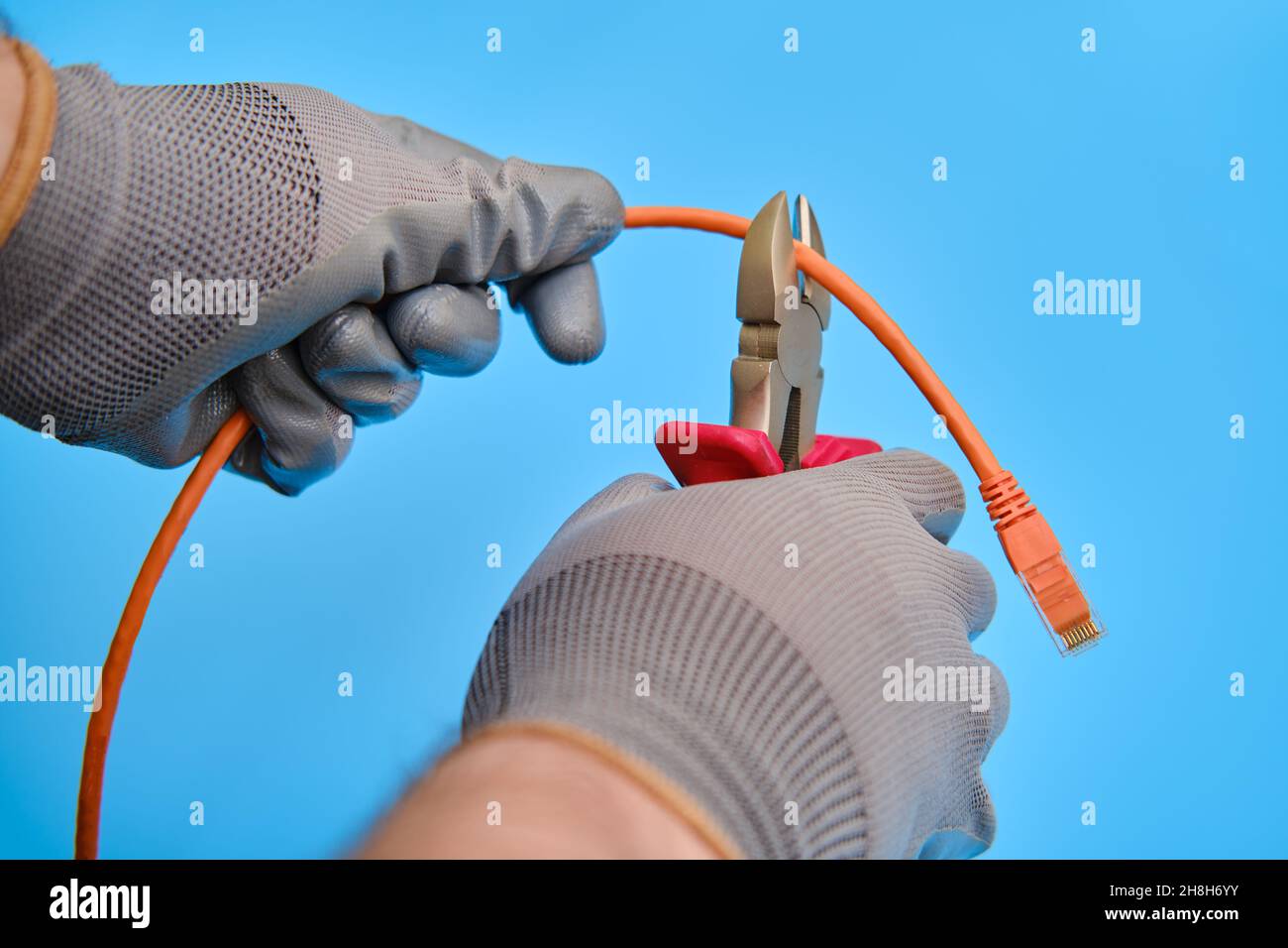 Cutting a computer network wire with wire cutters, blue studio ...
