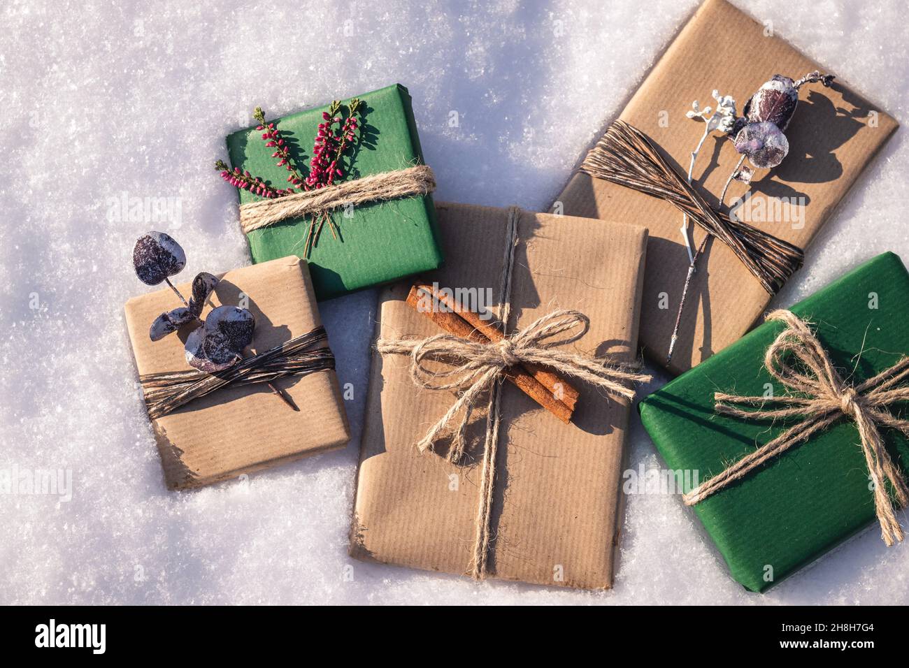 Wrapped Christmas presents with decoration in snow. Flat lay of gift boxes  in green and brown kraft wrapping paper Stock Photo - Alamy
