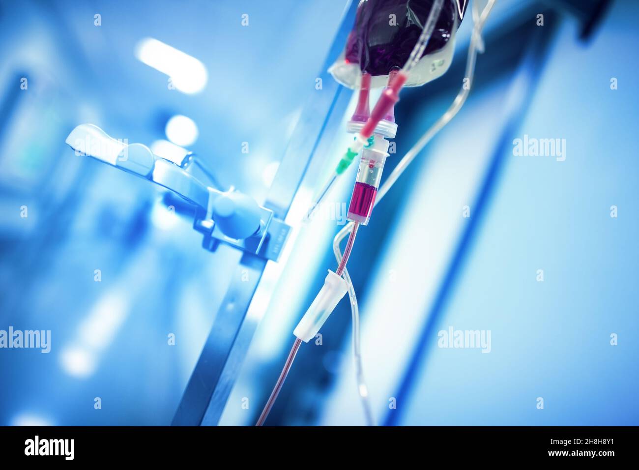 Blood transfusion system hanging on the iron pole ready to use in the hospital hall. Stock Photo