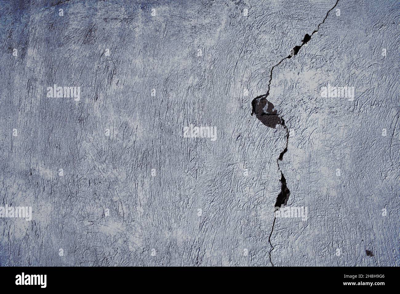 Cracked concrete wall with damaged surface, textured background. Stock Photo