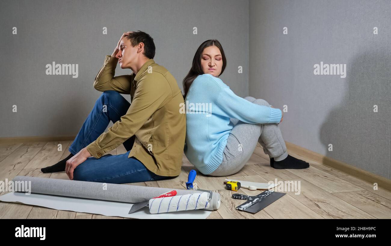 Young couple sits in dark room after quarrel over renovations Stock Photo