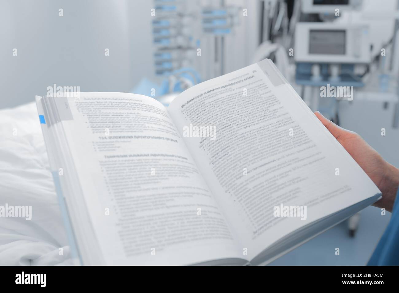Medical worker reads book on his post at the patient's bedside. Stock Photo