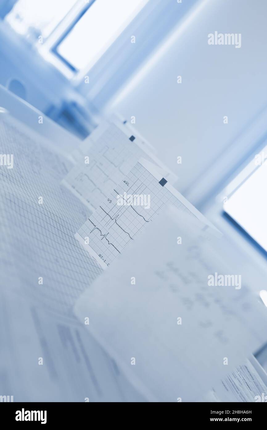 Bended ECG paper on the doctor's table against the window. Stock Photo