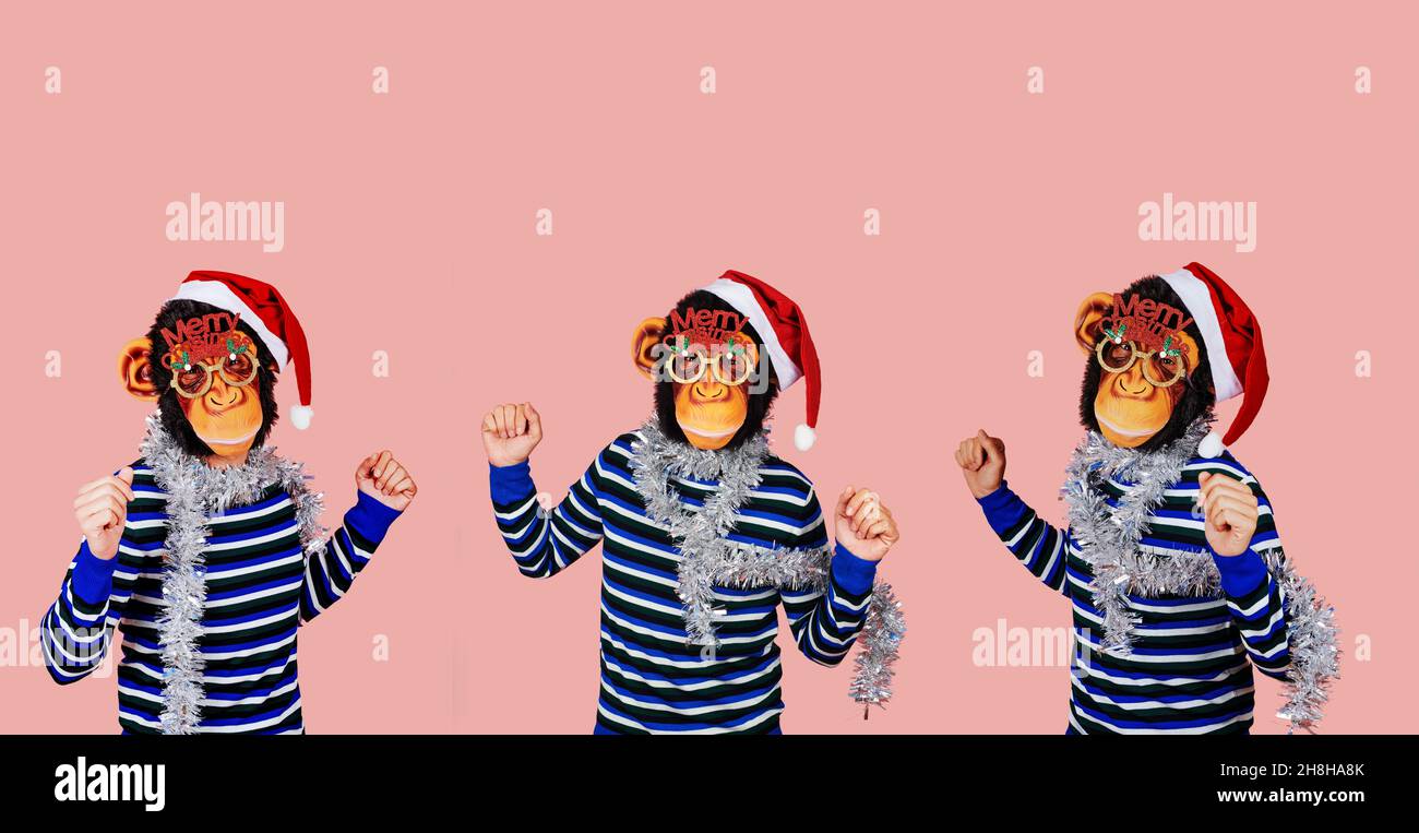 three men dancing wearing monkey masks, santa hats, eyeglasses with the sentence merry christmas, and strips of silver tinsel around their necks, on a Stock Photo