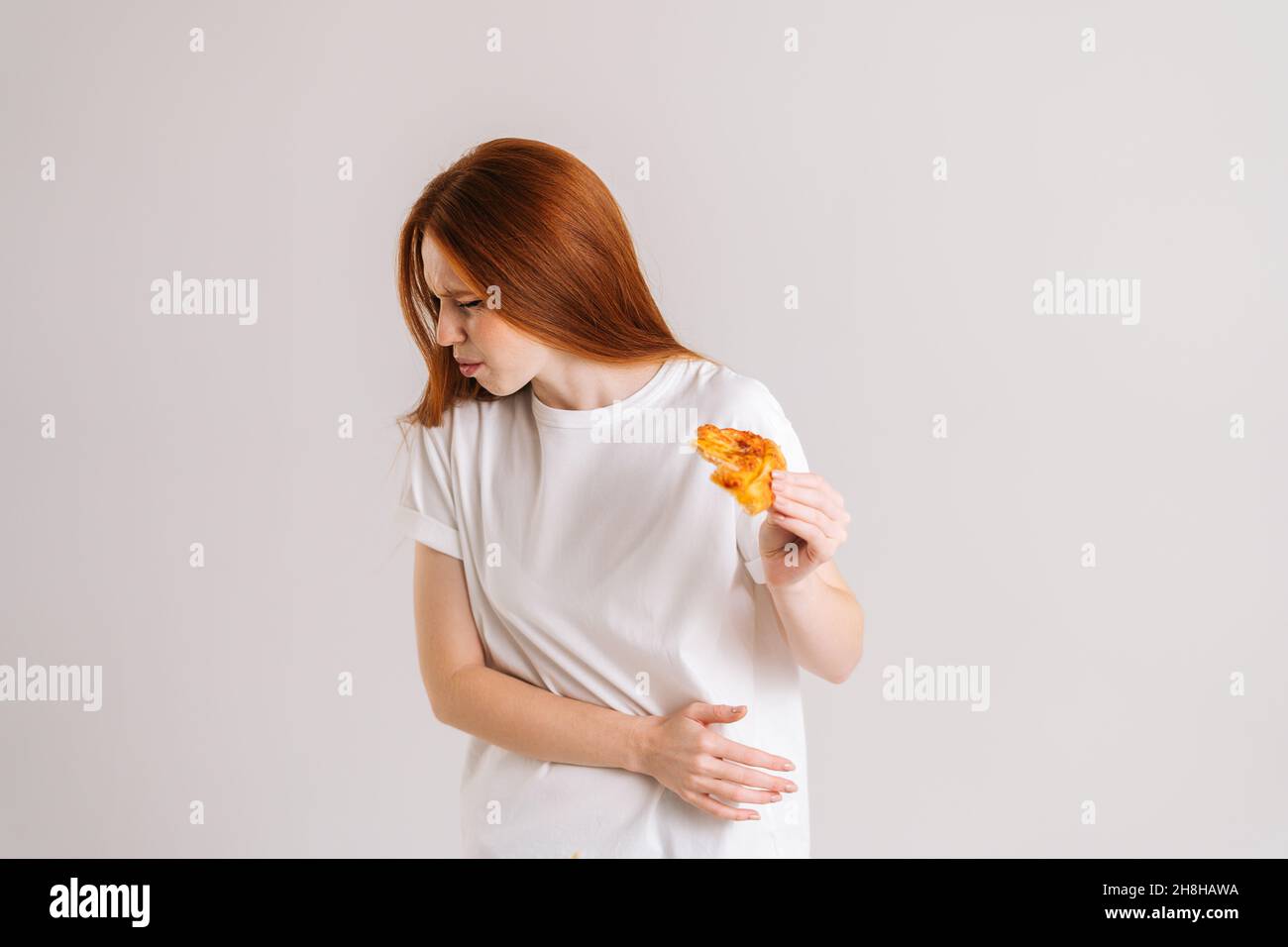 Studio portrait of sick young woman closed eyes feeling pain in stomach after eating pizza