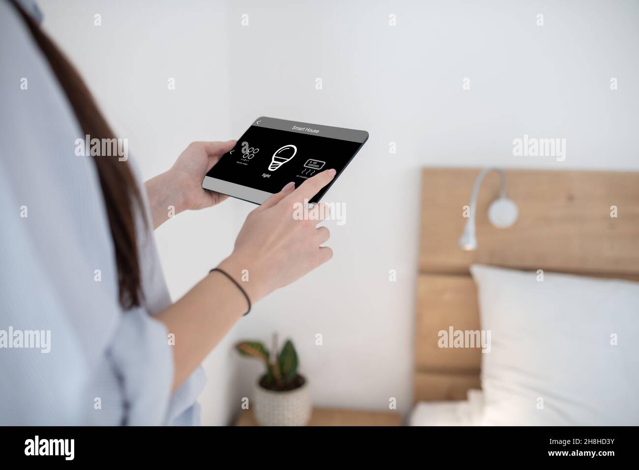 Woman turning on light using a tablet Stock Photo