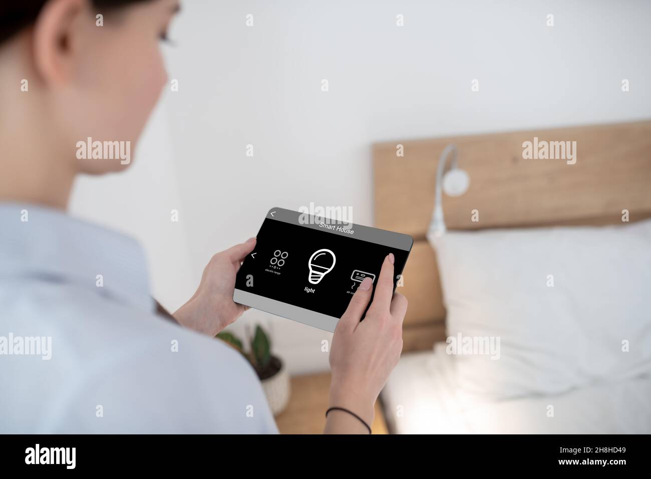 Female turning on light using a remote control Stock Photo