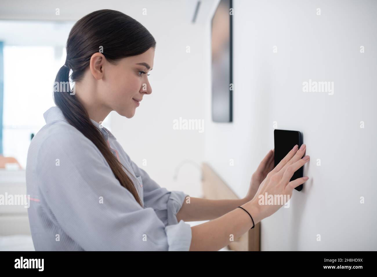 Focused calm dark-haired lady mounting a gadget Stock Photo