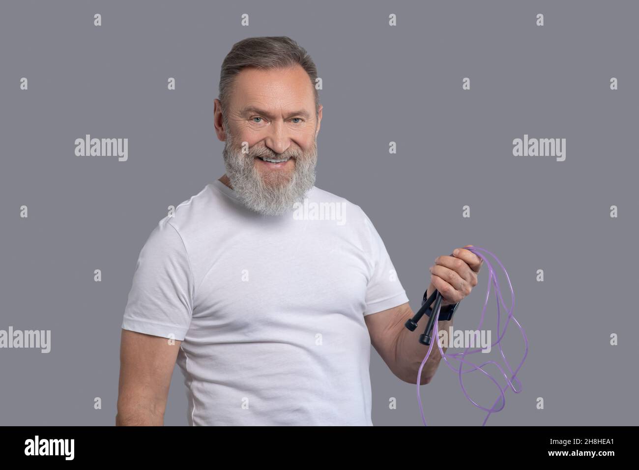 A smiling positive man with a jump rope in hands Stock Photo - Alamy