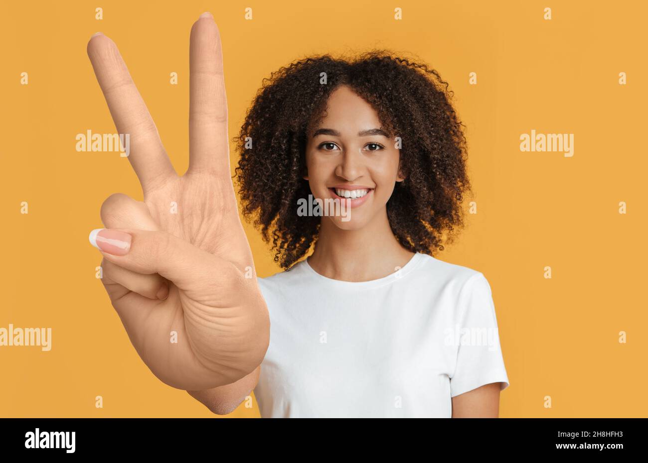 Cheerful mixed race young lady showing peace gesture Stock Photo