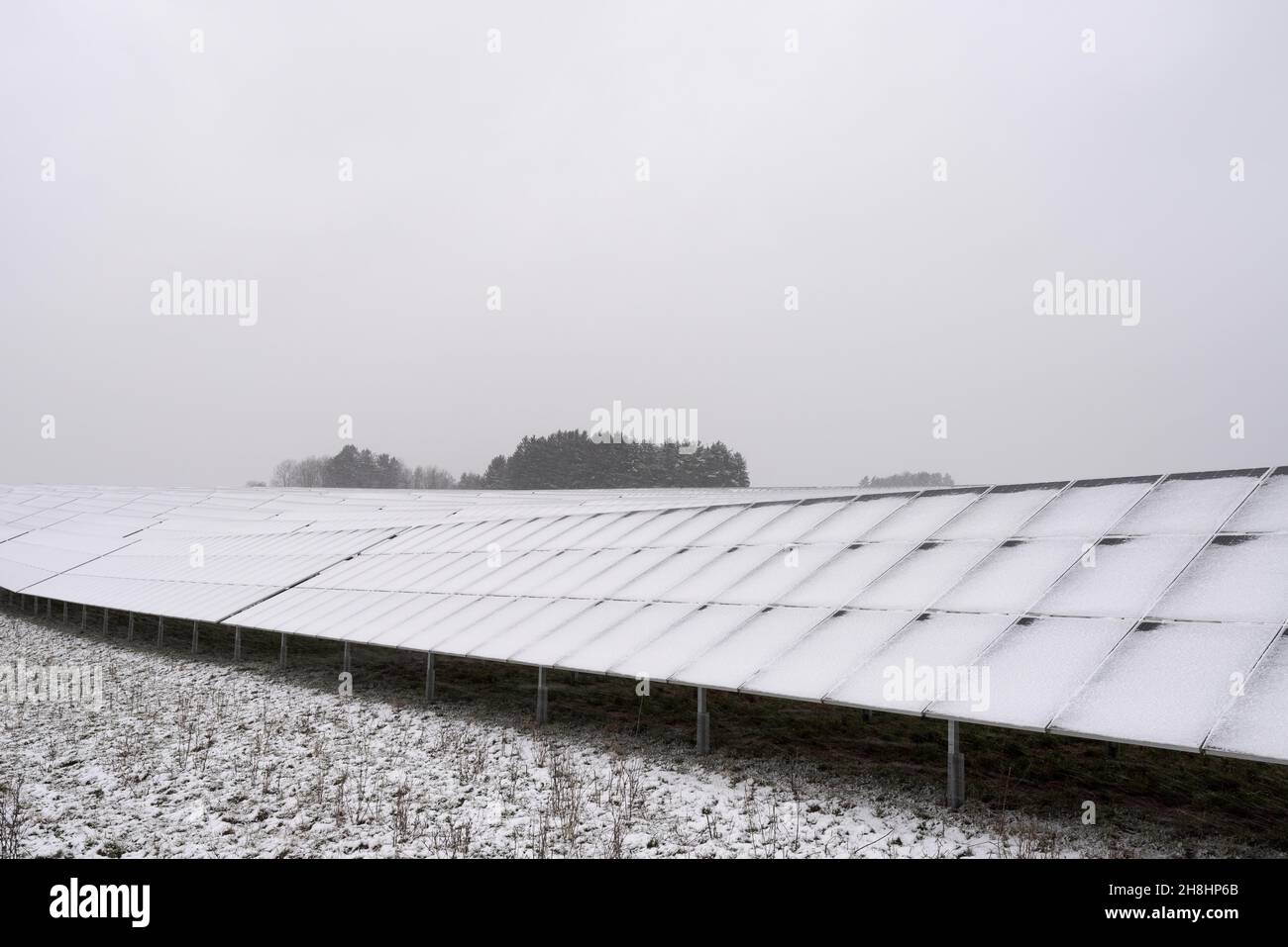 Array of solar modules in solar park on field completely covered with snow in winter during blizzard snow storm Stock Photo