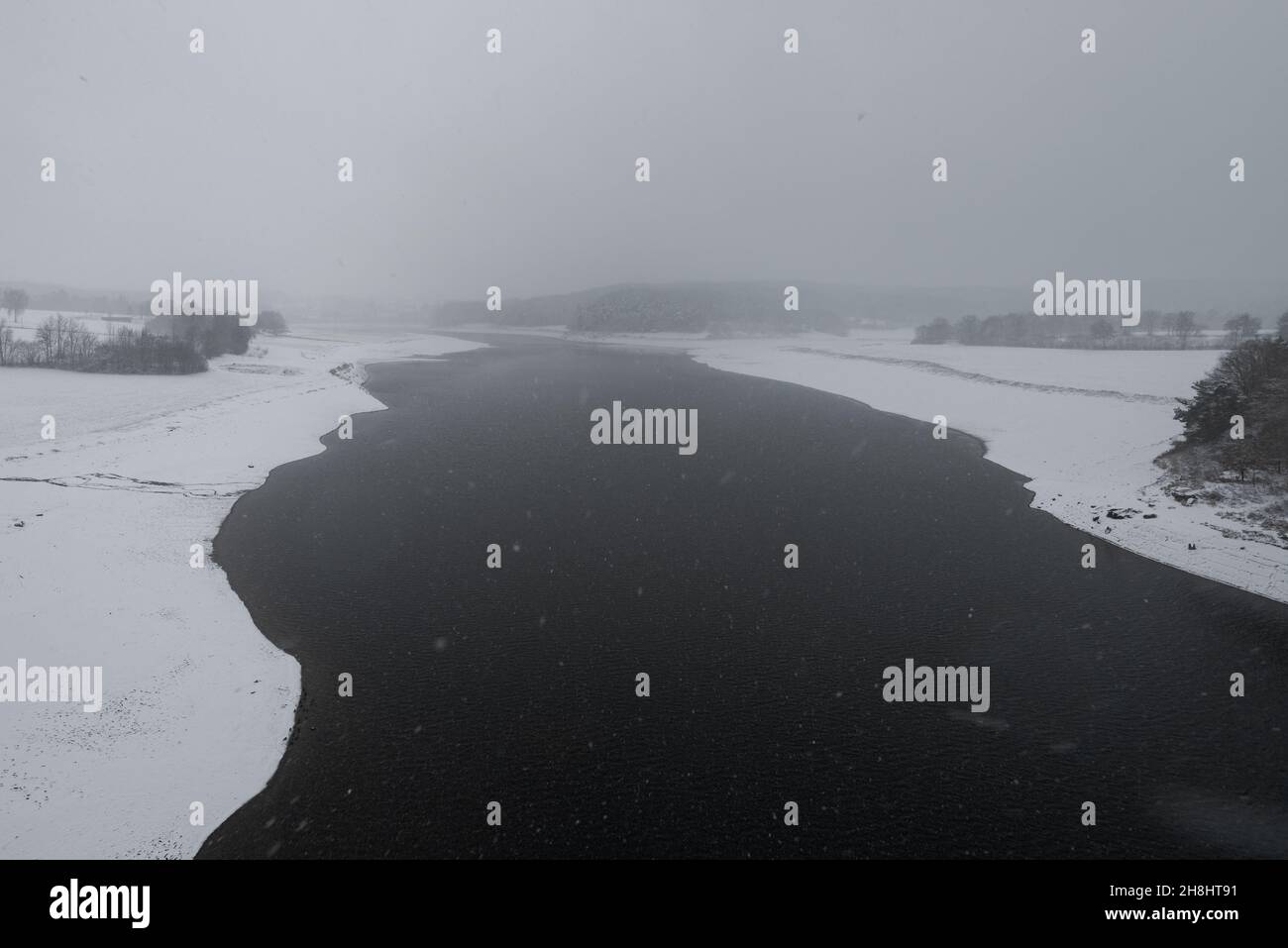 The reservoir lake on the dam in Eixendorf in winter with snow during snow storm seen from bridge above Stock Photo