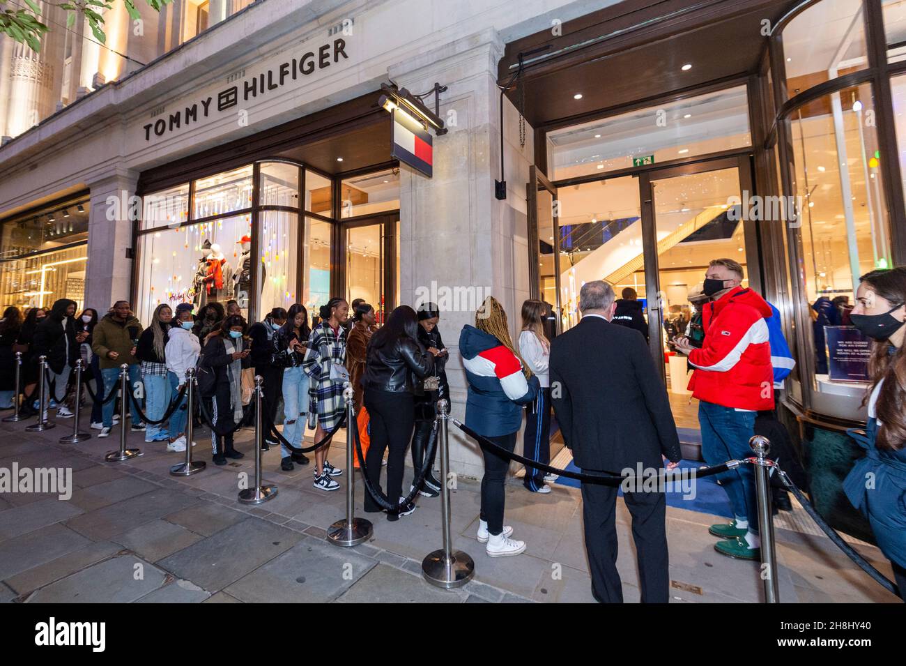 London, UK. 30 November 2021. Invited guests and 'influencers' wait to  enter the Tommy Hilfiger store on Regent Street. They will see a public  appearance inside with designer Tommy Hilfiger and Nigerian