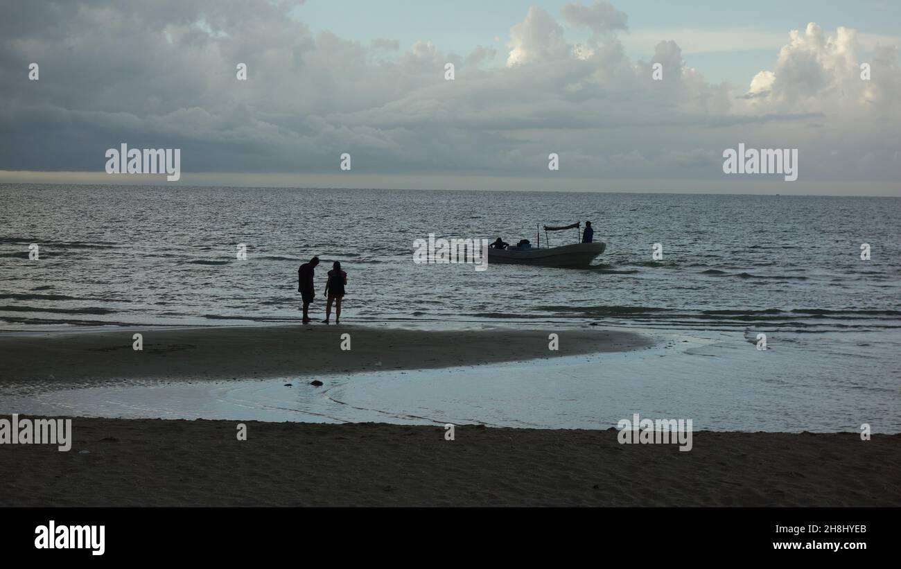 Enjoying the sunset in the beach. Fishers boats. Stock Photo