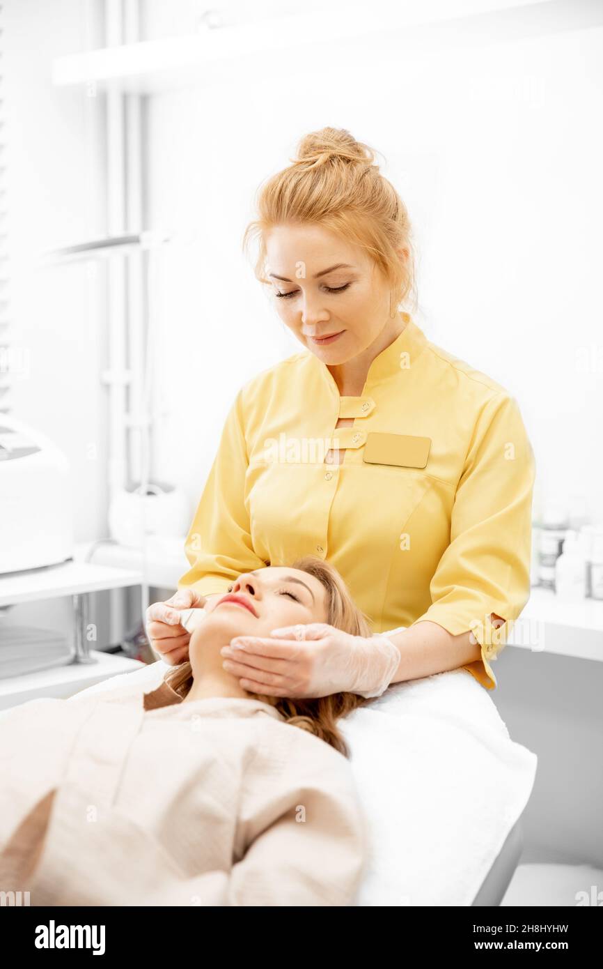 Doctor applies anti wrinkle aging cream skin of young woman in beauty ...