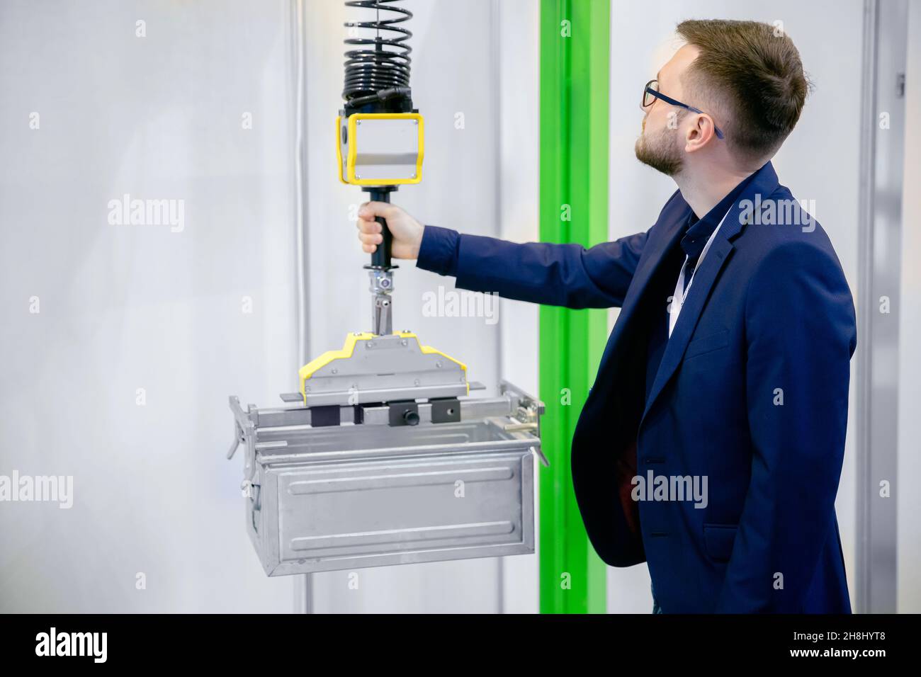 Worker engineer uses intelligent industrial manipulator lift easy with gripper in factory. Stock Photo