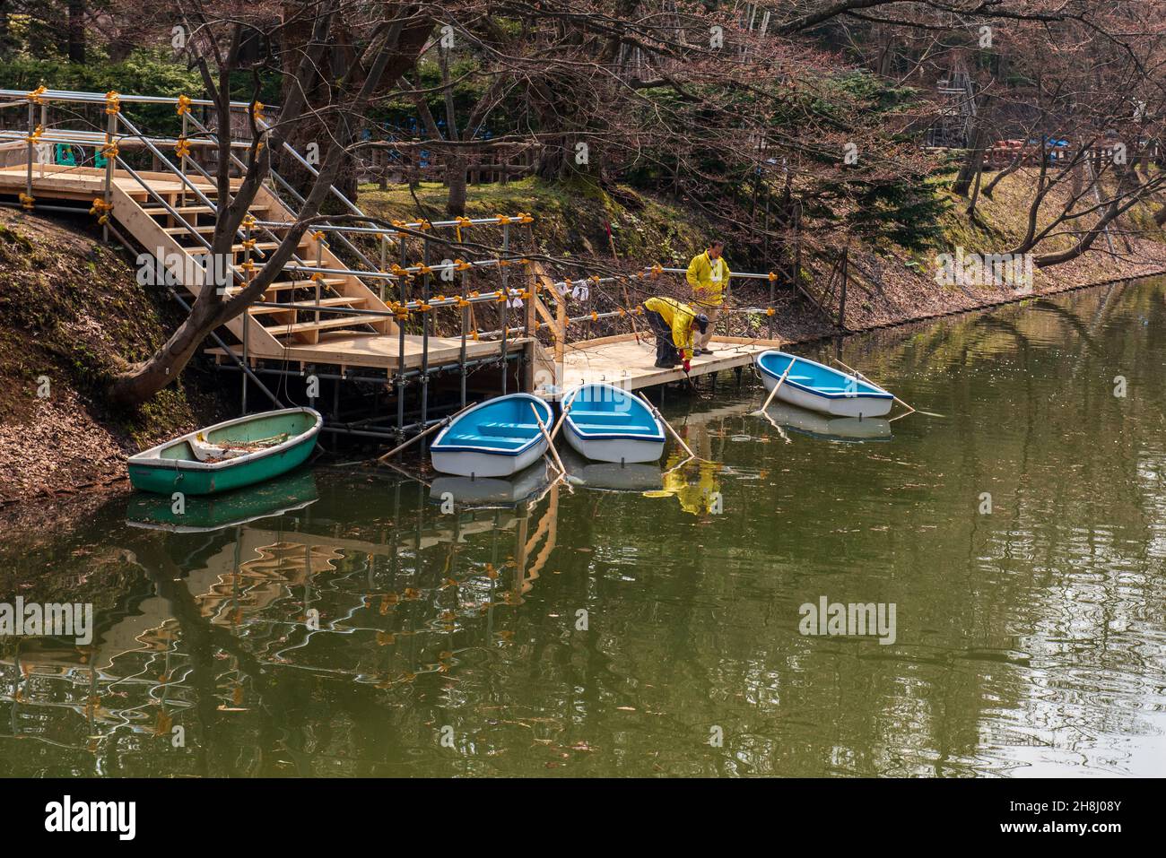 Aomori, Japan  Workers in yelloe jackets secure rowboats at a dock. Stock Photo