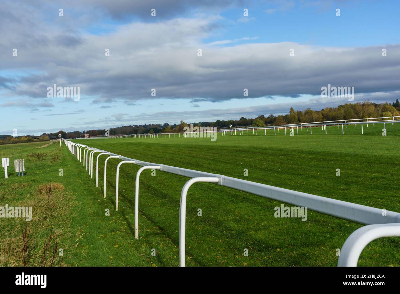 Long straight flat horse racing track with long white railings on each