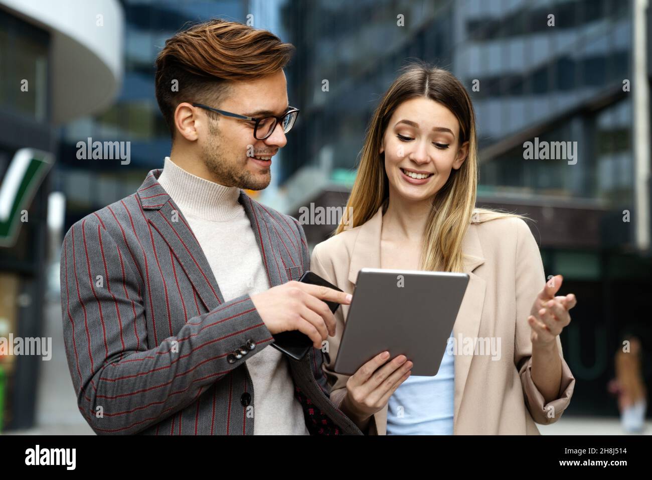 Successful young business people talking, working together in front of modern business building Stock Photo