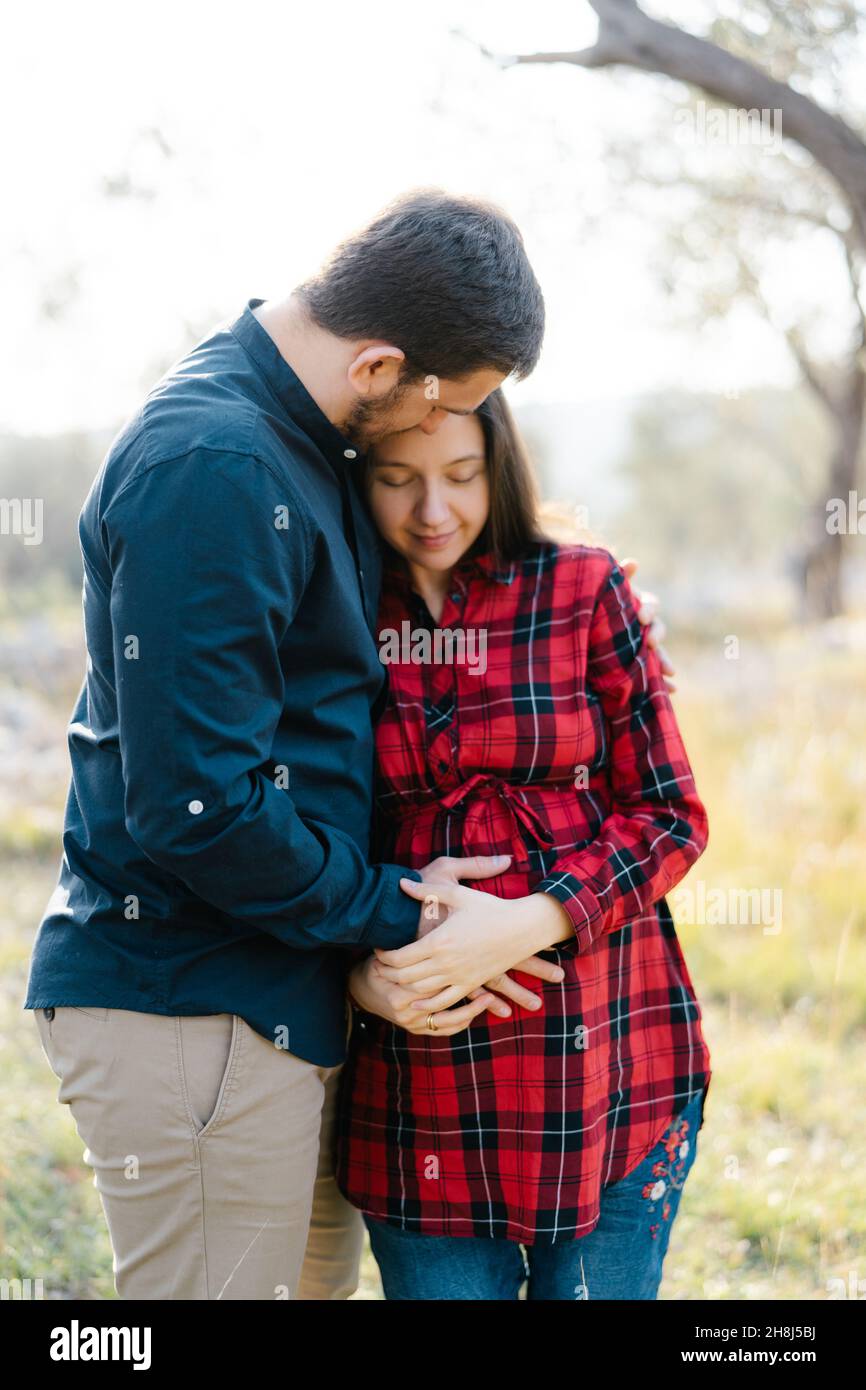 Man hugs a pregnant woman while holding his hand on her belly Stock ...