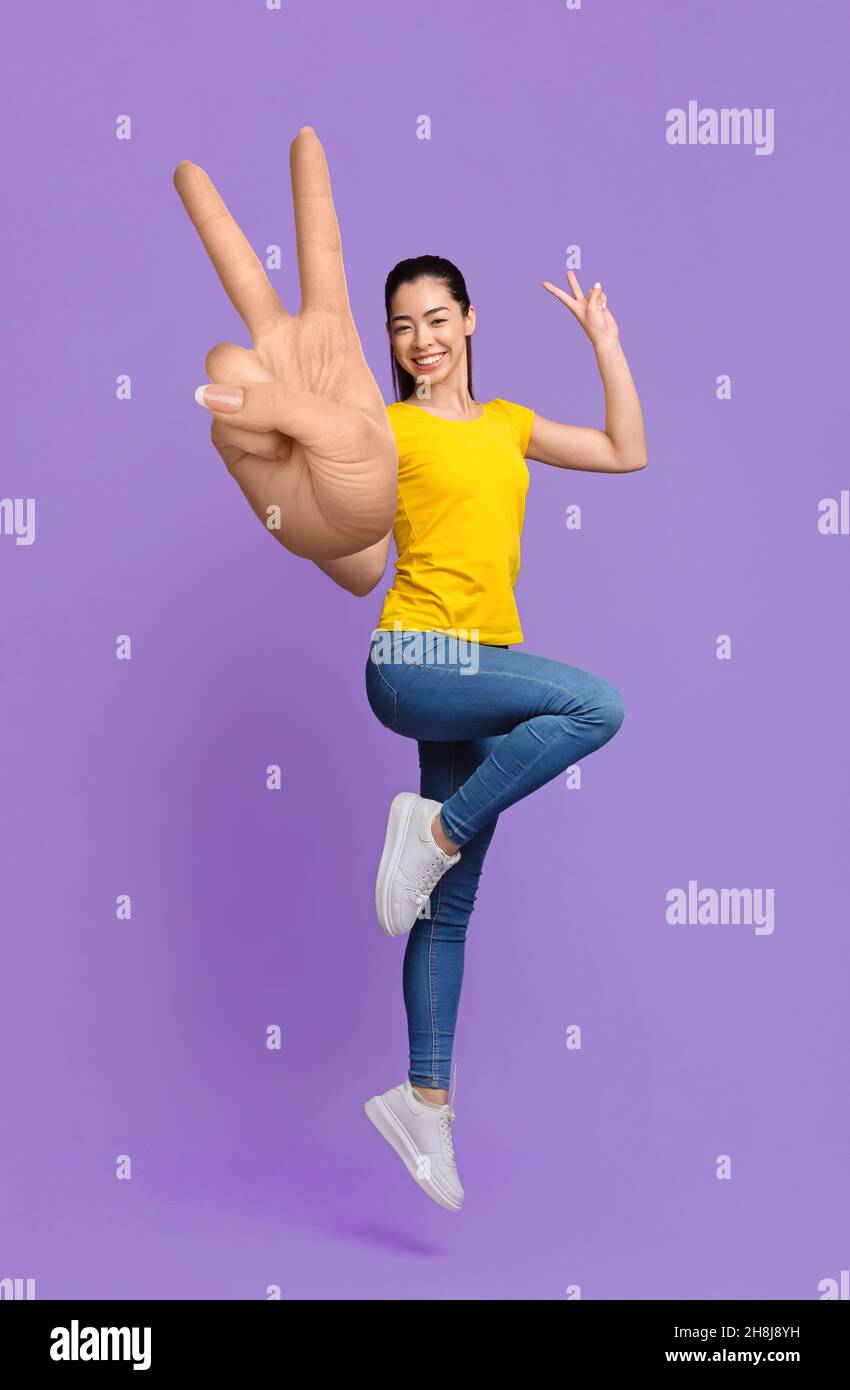 Cheerful Asian Girl Jumping In Air And Showing Peace Gesture Stock ...