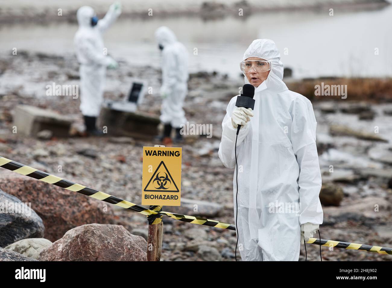 Portrait of woman wearing protective suit protesting toxic waste and pollution at ecological disaster site, copy space Stock Photo