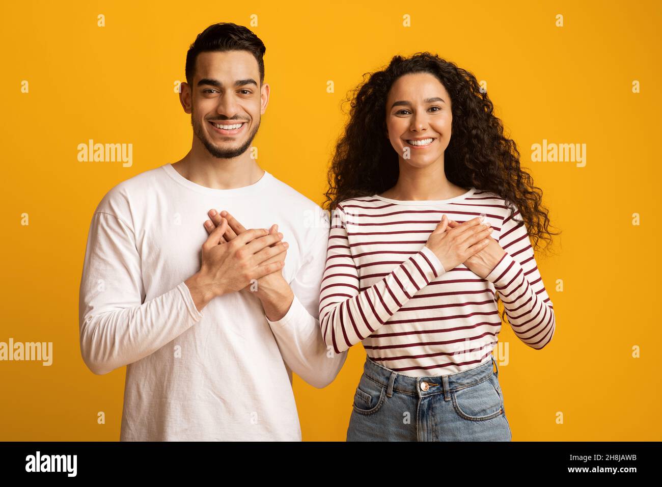 Gratitude Concept. Thankful Middle Eastern Couple Keeping Both Palms On Chest Stock Photo