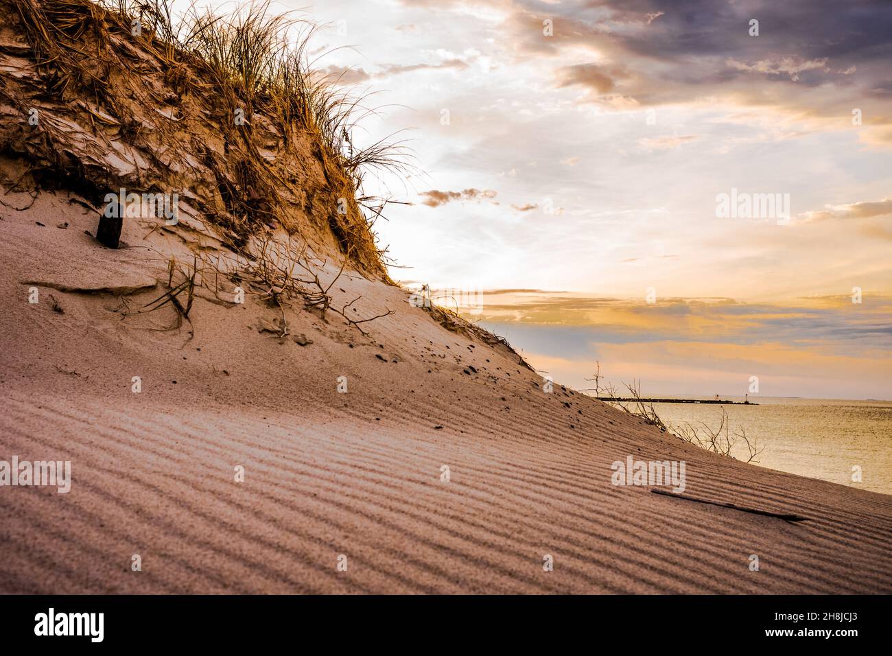 The constantly moving storm clouds and the swirling wind created the ripple affect in front of this sand dune. The erosion dunes can be beautiful. Stock Photo