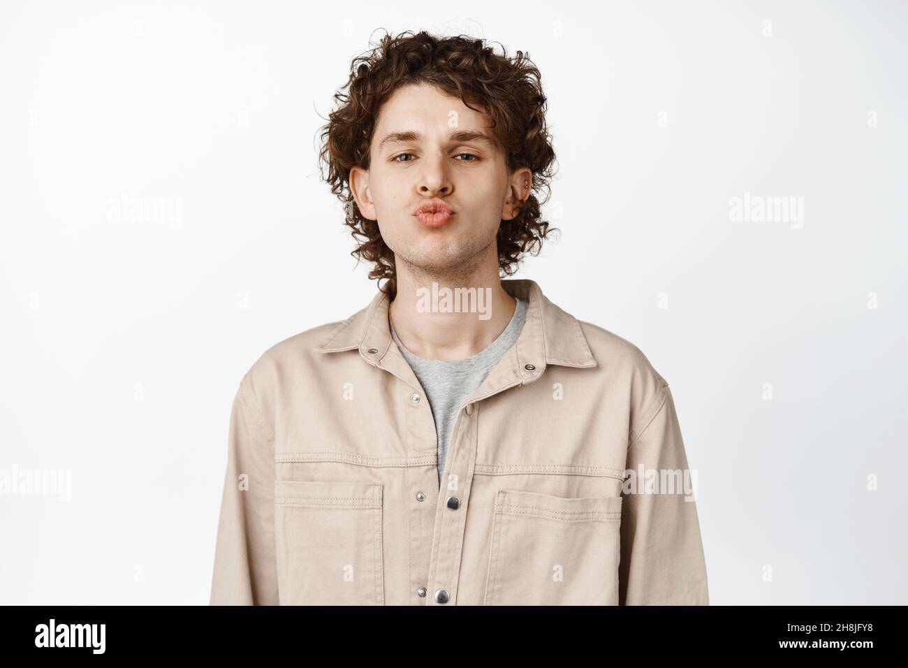 Close up of cute curly guy kissing, pucker lips and looking funny at ...