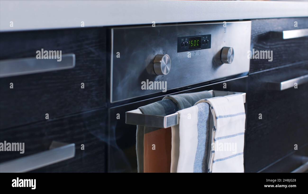 Closeup of white smoke coming out of a stainless steel electric oven