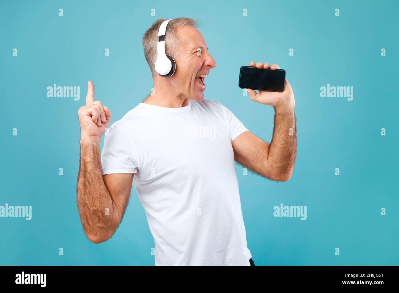 Happy mature man singing using smartphone as mic Stock Photo