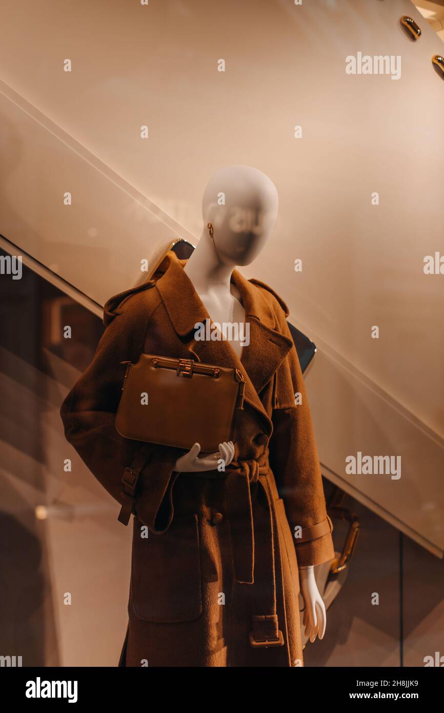 A mannequin dressed in a stylish brown long coat and holding a female leather handbag in the hands. Autumn winter fashion collection Stock Photo