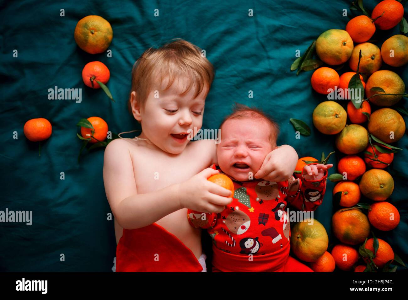 The older brother wants to feed the Christmas newborn baby a tangerine