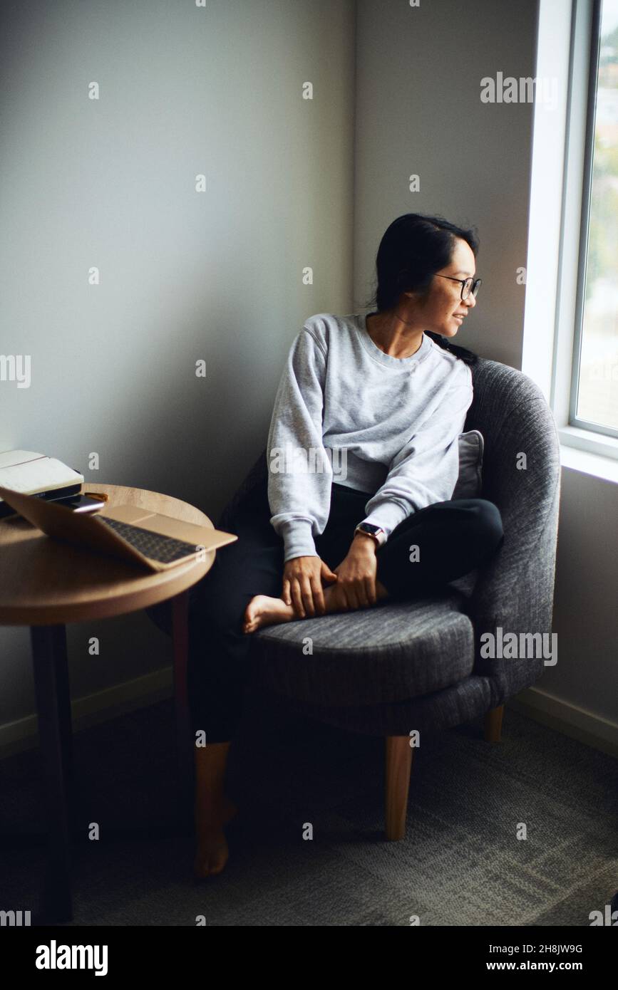 Woman sitting in an armchair looking out the window Stock Photo