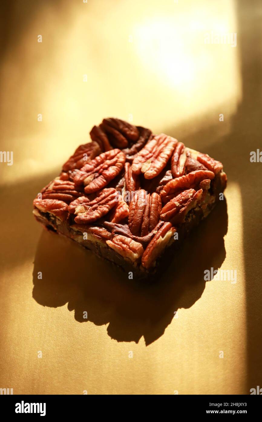 Single Brownie on shiny gold background with heavy shadows in studio photograph Stock Photo