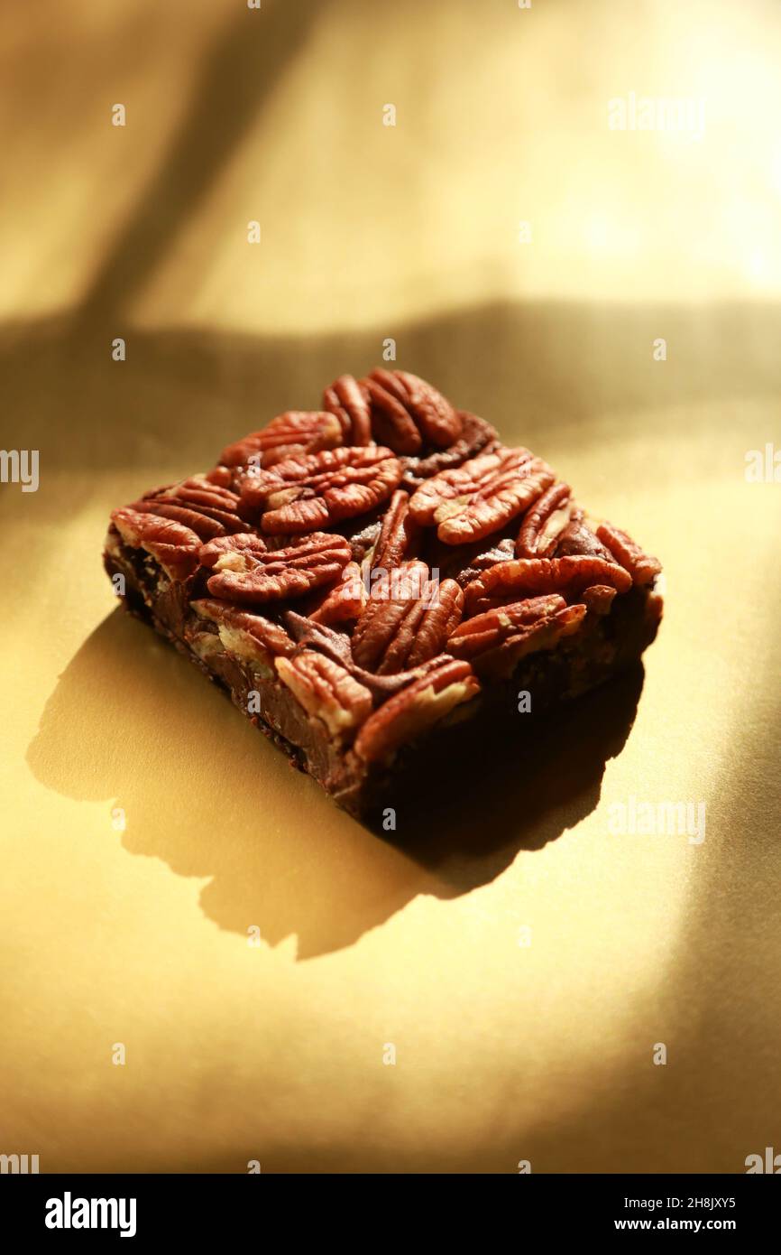 Single Brownie on shiny gold background with heavy shadows in studio photograph Stock Photo
