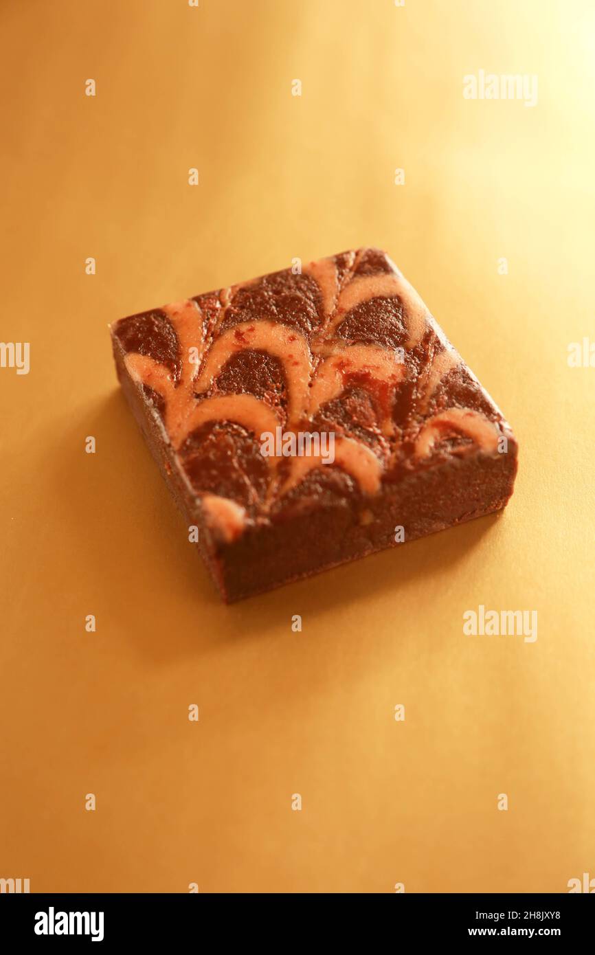 Single Brownie on shiny gold background in studio photograph Stock Photo