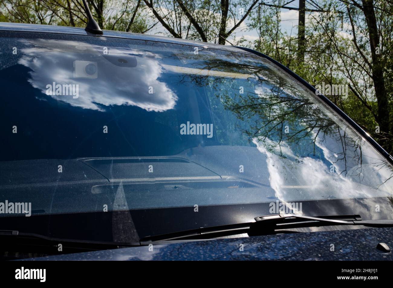Clouds reflection on the car window, modern car standing under the