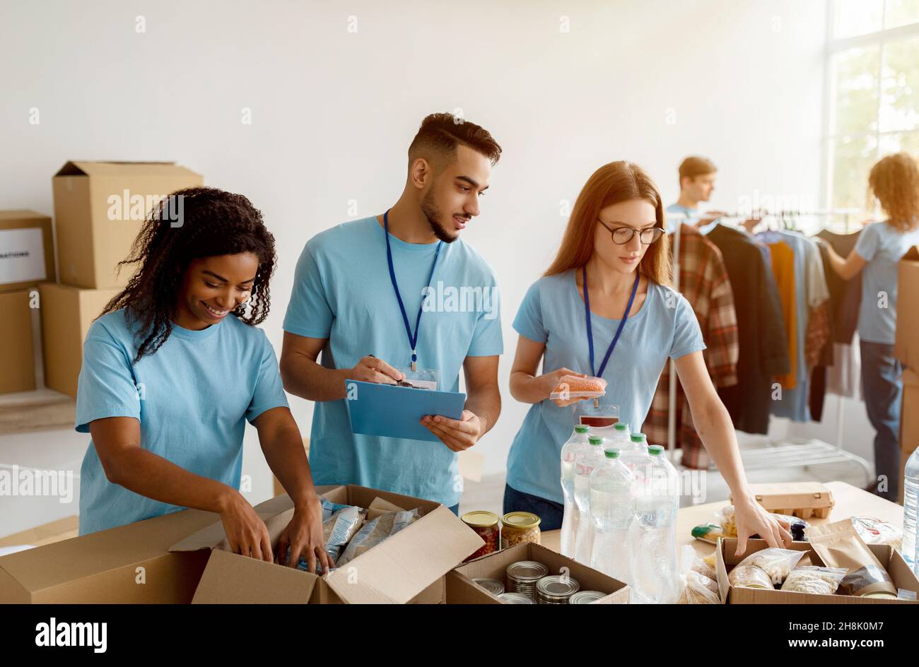 Young group of multiracial volunteers working in community charity donation center, sorting donated food in boxes Stock Photo