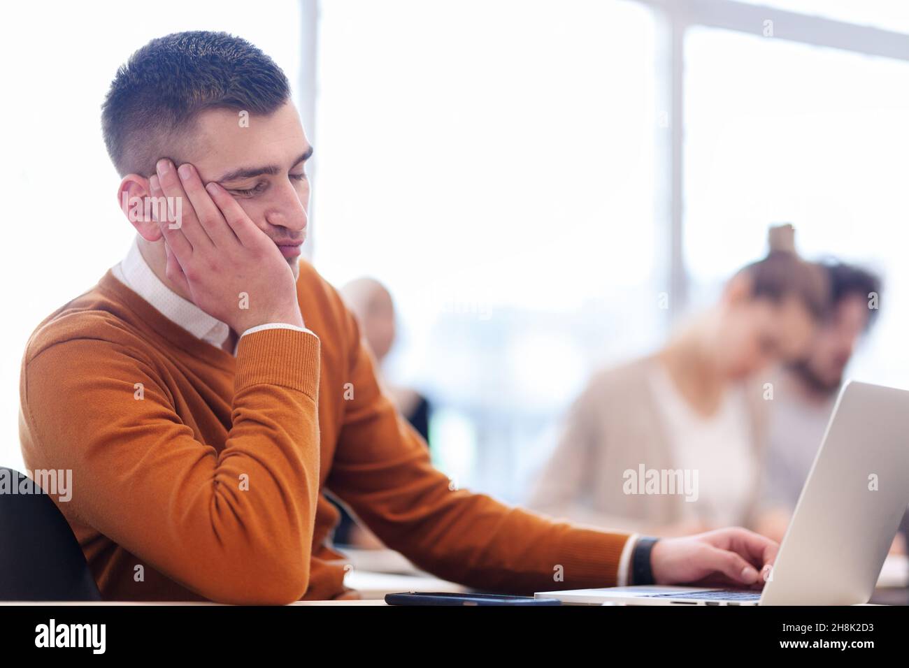 Students listening to a lecturer in a classroom. Young man sleeping during boring class. Stock Photo