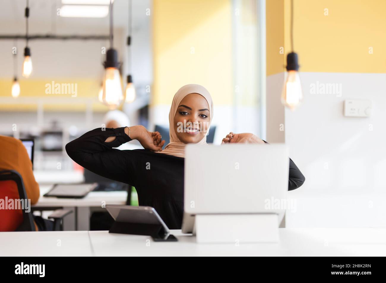 African american muslim girl with hijab working on a laptop in an ...
