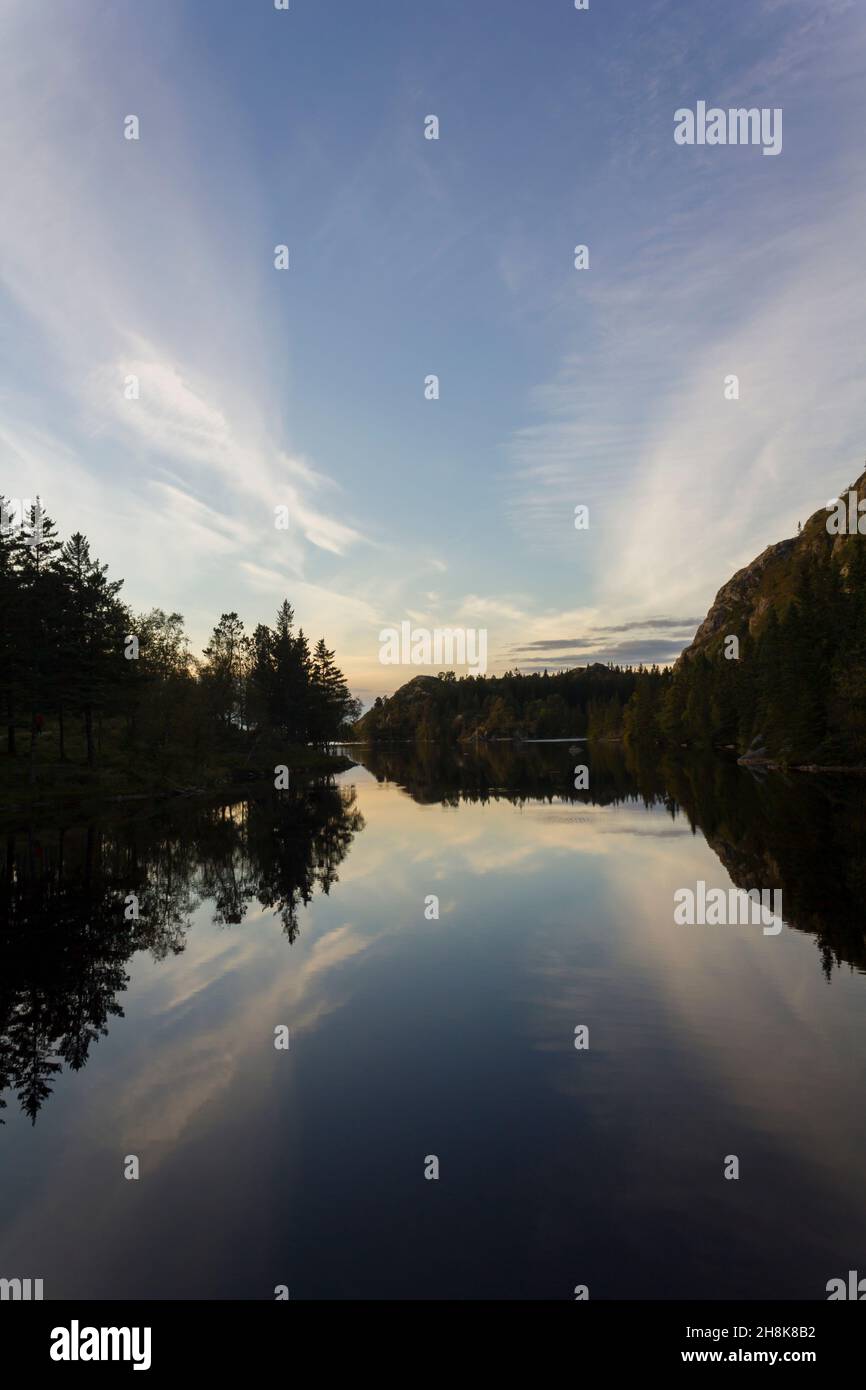 Trees and blue sky reflected on calm blue water Stock Photo - Alamy