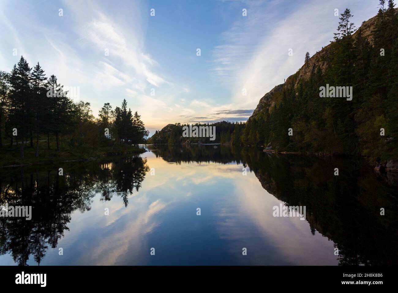 Trees and blue sky reflected on calm blue water Stock Photo - Alamy