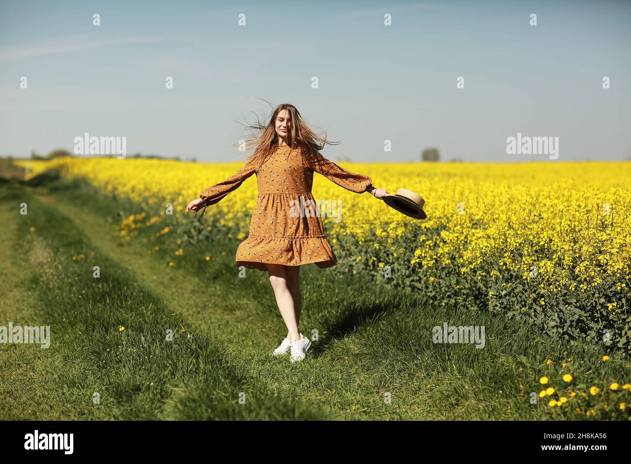 beautiful young woman walks in a field of yellow rapeseed. Girl ...