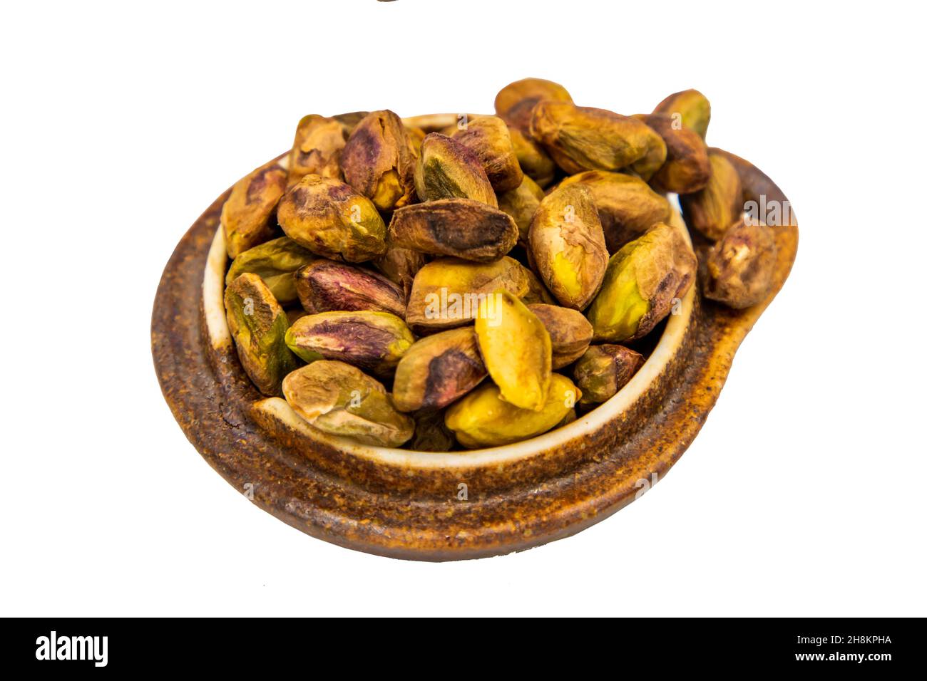 Shelled pistachios nuts kernels on wooden cup isolated on white