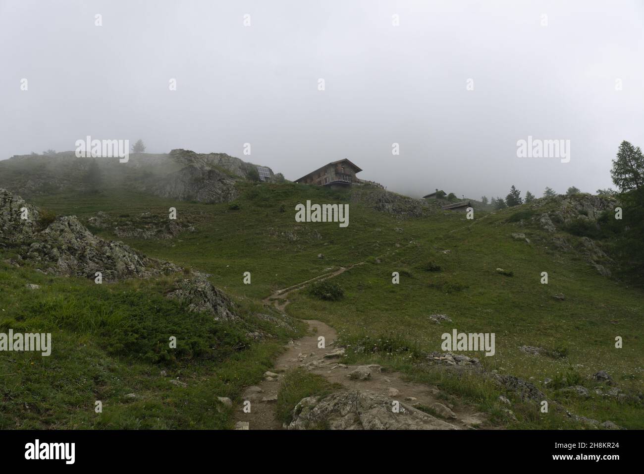 Natural view of a trail with rocky hills and grass area on a foggy day ...