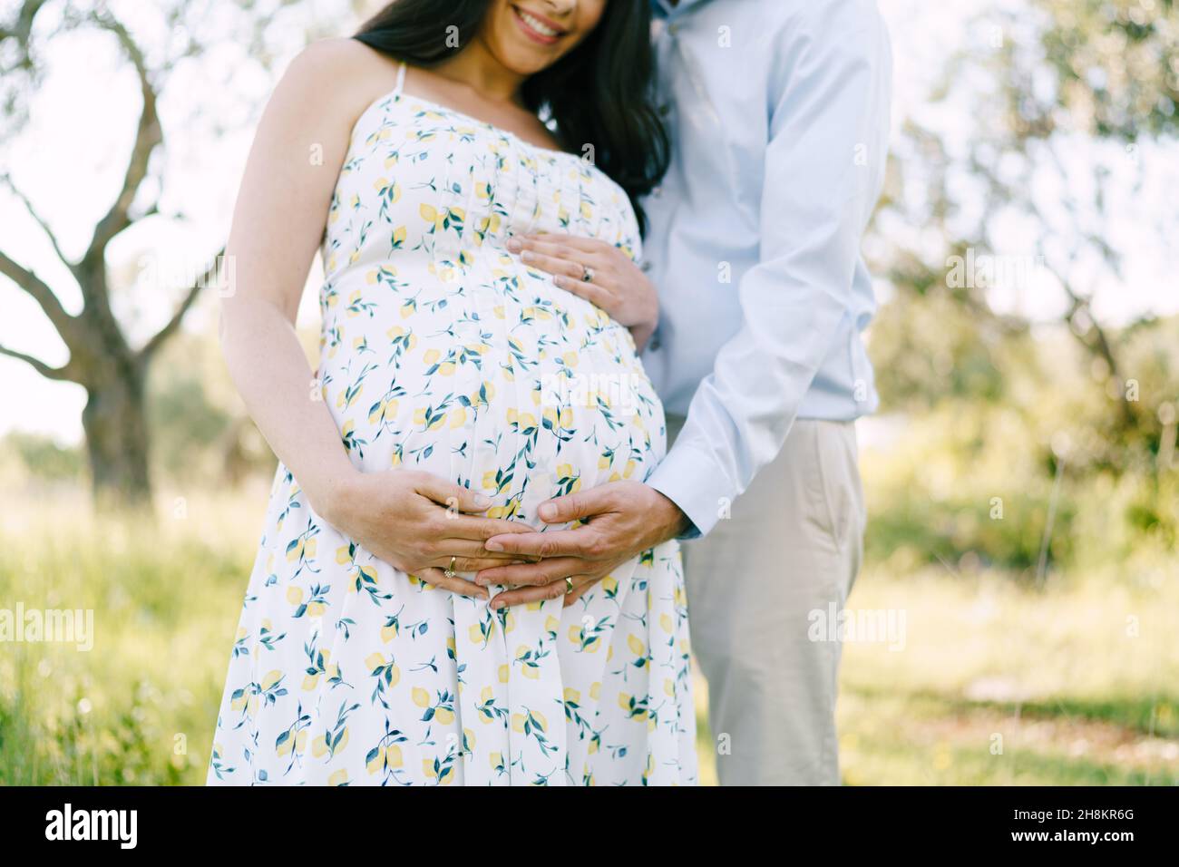 Man hugs a woman pregnant belly in the park. Close-up Stock Photo - Alamy